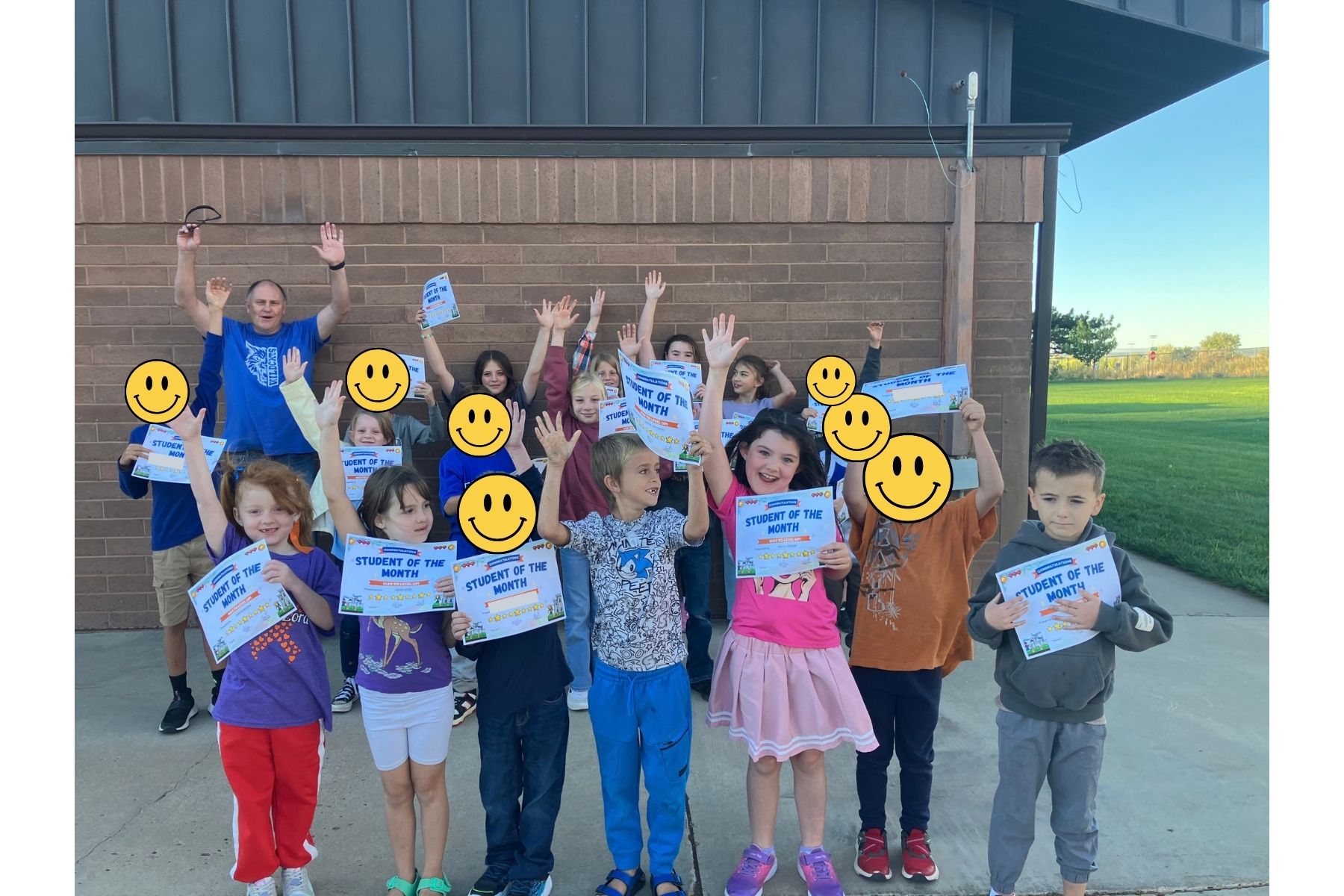 September 2026 Students of the Month and Staff Member of the Month standing outside the school and cheering
